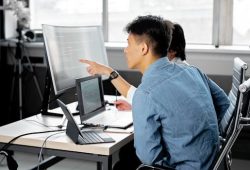 Professionals collaborating at a tech-centric workspace with laptops and monitors.